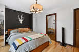 This cozy bedroom features a stylish design with a striking black accent wall, complemented by a unique deer head decor.