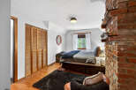 This cozy bedroom features a rustic brick accent wall and a charming wooden closet.