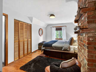 This cozy bedroom features a rustic brick accent wall and a charming wooden closet.