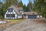 This charming Tudor-style home boasts a unique architectural design with its distinctive black and white exterior and a red front door.