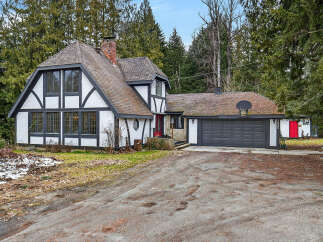 This charming Tudor-style home boasts a unique architectural design with its distinctive black and white exterior and a red front door.