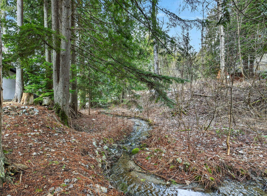Discover a serene oasis with this property featuring a tranquil stream winding through lush greenery.
