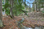 Discover a serene oasis with this property featuring a tranquil stream winding through lush greenery.