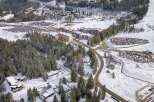 This stunning aerial view showcases a picturesque winter landscape, highlighting a charming property nestled amidst snow-covered trees.