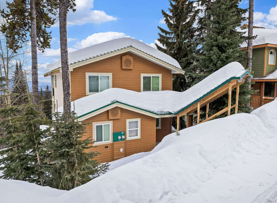This charming mountain home offers a cozy retreat with its snow-covered roof and inviting facade.