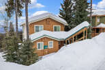 This charming mountain home offers a cozy retreat with its snow-covered roof and inviting facade.