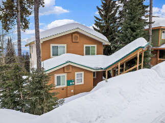 This charming mountain home offers a cozy retreat with its snow-covered roof and inviting facade.