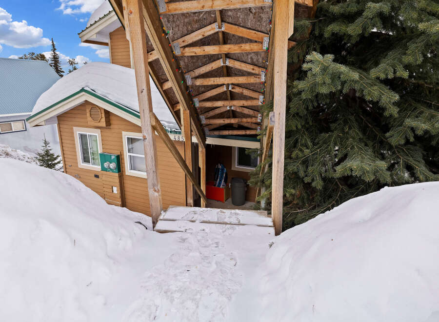 This charming property offers a cozy retreat with a covered entrance and a snow-covered landscape.