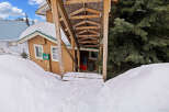 This charming property offers a cozy retreat with a covered entrance and a snow-covered landscape.