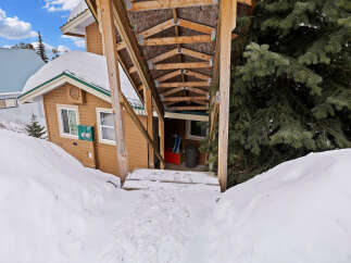 This charming property offers a cozy retreat with a covered entrance and a snow-covered landscape.