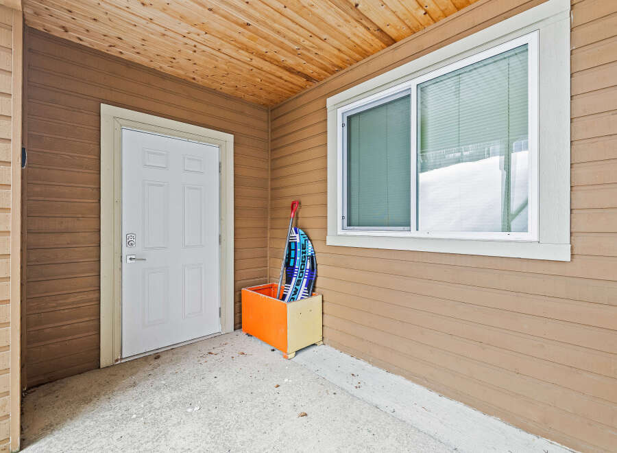 This charming property boasts a welcoming entrance with a bright white door and a convenient storage box.