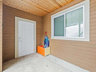 This charming property boasts a welcoming entrance with a bright white door and a convenient storage box.