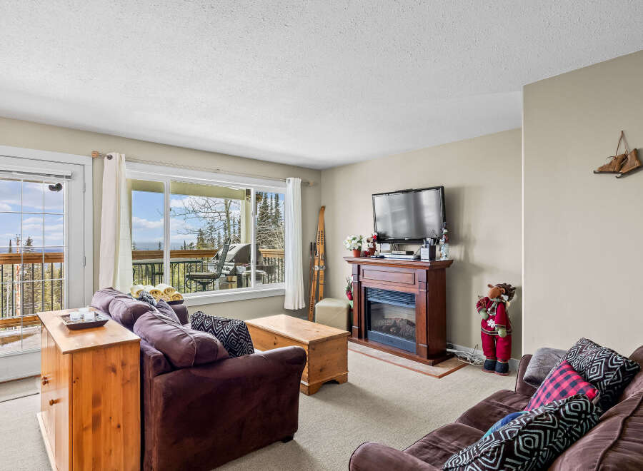 This cozy living room boasts a warm fireplace, perfect for chilly evenings, and a large window offering stunning views.