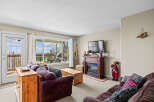 This cozy living room boasts a warm fireplace, perfect for chilly evenings, and a large window offering stunning views.