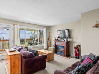 This cozy living room boasts a warm fireplace, perfect for chilly evenings, and a large window offering stunning views.