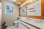 This charming bathroom features a bright and airy design with a large mirror and a stylish vanity.