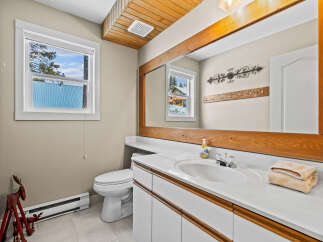 This charming bathroom features a bright and airy design with a large mirror and a stylish vanity.