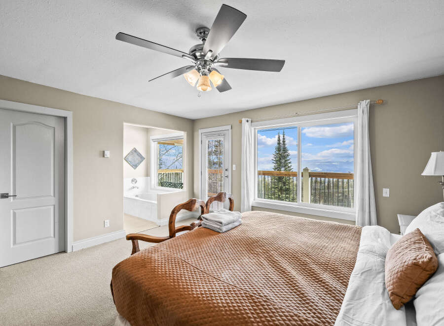 Experience the tranquility of this stunning bedroom, featuring a cozy bed and a breathtaking view.