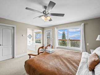 Experience the tranquility of this stunning bedroom, featuring a cozy bed and a breathtaking view.