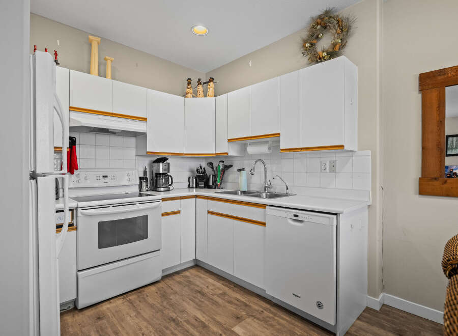 This charming kitchen boasts a bright and airy atmosphere with its pristine white cabinetry and appliances.