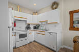 This charming kitchen boasts a bright and airy atmosphere with its pristine white cabinetry and appliances.