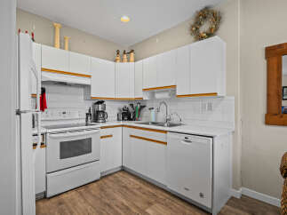 This charming kitchen boasts a bright and airy atmosphere with its pristine white cabinetry and appliances.