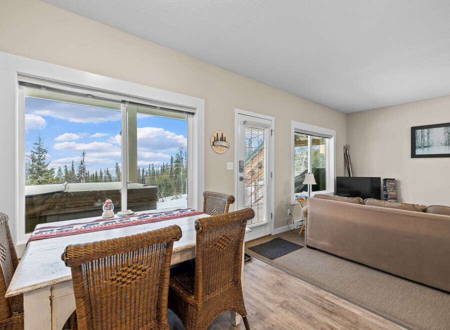 This cozy living space features a dining area with a rustic table and wicker chairs, perfect for enjoying meals with a view.