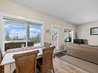 This cozy living space features a dining area with a rustic table and wicker chairs, perfect for enjoying meals with a view.