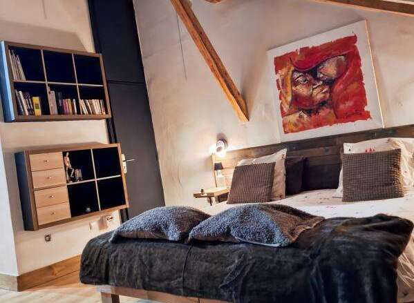 Discover the charm of this unique property, featuring a cozy bedroom with exposed wooden beams and a striking piece of art.