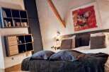 Discover the charm of this unique property, featuring a cozy bedroom with exposed wooden beams and a striking piece of art.