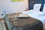 This cozy bedroom features a comfortable bed with soft linens and a stylish throw blanket, perfect for a relaxing stay.