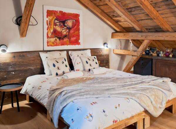 Discover the charm of this cozy bedroom, featuring a unique wooden bed frame and a rustic wooden ceiling.