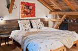Discover the charm of this cozy bedroom, featuring a unique wooden bed frame and a rustic wooden ceiling.