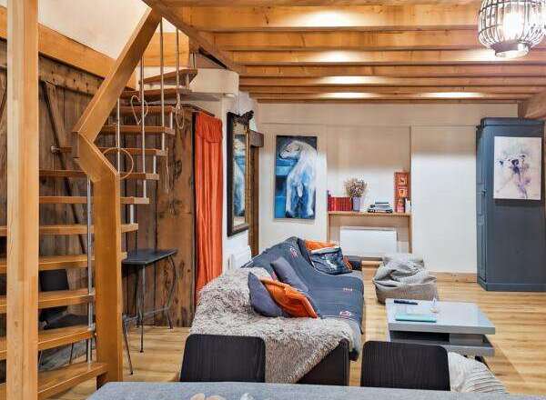This charming property boasts a cozy living space with exposed wooden beams and a unique staircase.