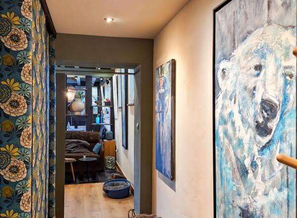 Discover the charm of this inviting hallway, featuring elegant wooden floors and artistic wall decor.