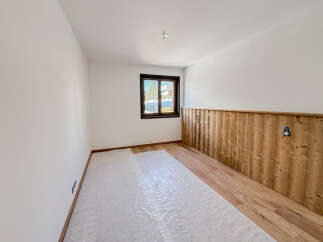 This inviting room features a warm wooden accent wall and hardwood flooring, creating a cozy and stylish atmosphere.