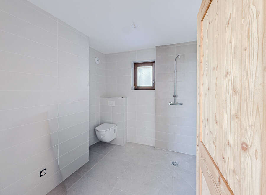 This modern bathroom features sleek, neutral-toned tiles and a minimalist design, creating a clean and inviting space.