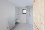 This modern bathroom features sleek, neutral-toned tiles and a minimalist design, creating a clean and inviting space.
