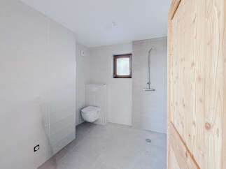 This modern bathroom features sleek, neutral-toned tiles and a minimalist design, creating a clean and inviting space.