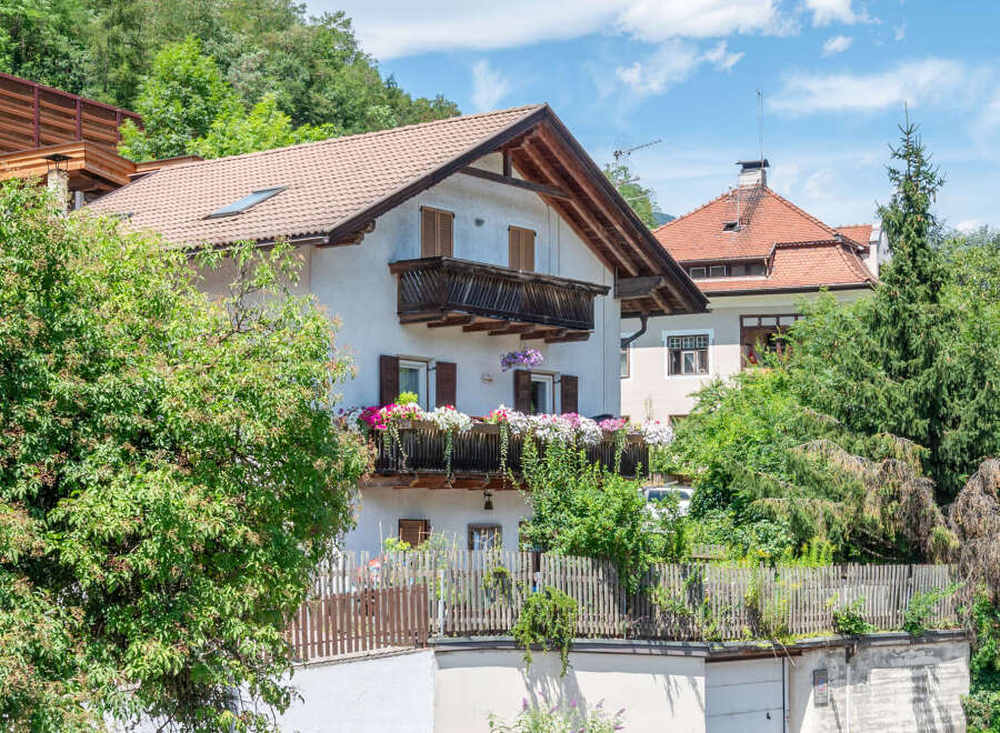 Charming alpine home featuring a traditional wooden balcony overflowing with vibrant flowers, perfect for enjoying mountain views.