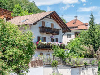 Charming alpine home featuring a traditional wooden balcony overflowing with vibrant flowers, perfect for enjoying mountain views.