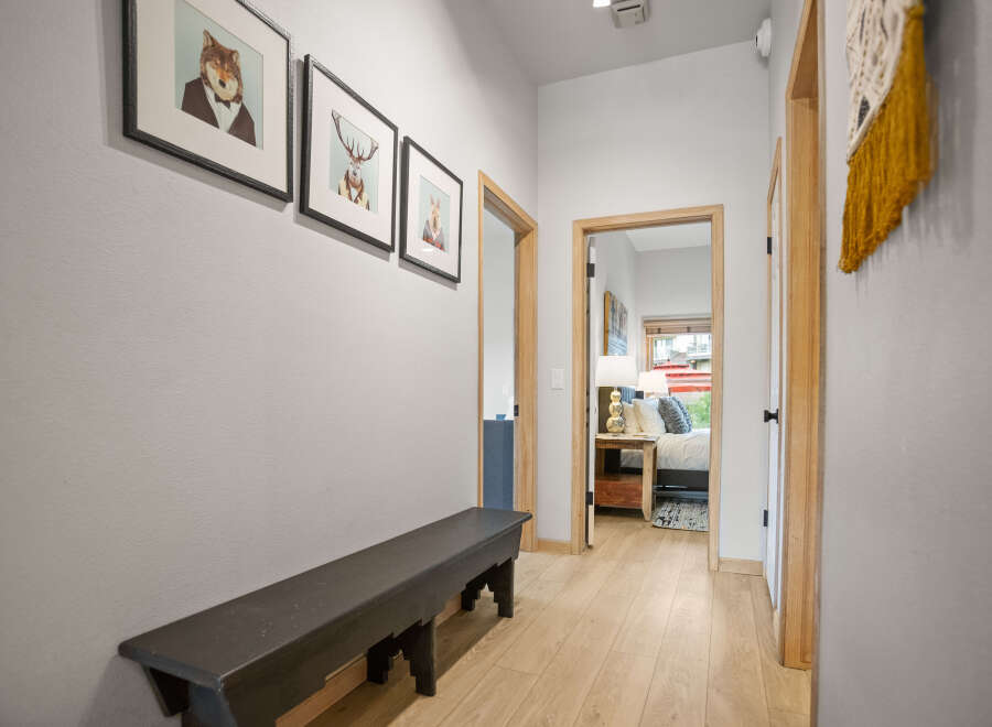 Step into this inviting hallway, featuring a stylish black bench and charming artwork.