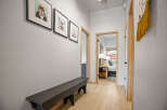 Step into this inviting hallway, featuring a stylish black bench and charming artwork.