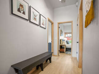 Step into this inviting hallway, featuring a stylish black bench and charming artwork.