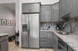 This stunning kitchen boasts modern gray cabinetry, complemented by a sleek stainless steel Whirlpool refrigerator.