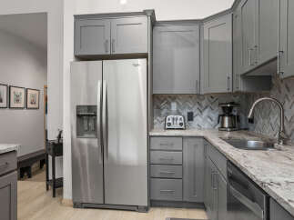 This stunning kitchen boasts modern gray cabinetry, complemented by a sleek stainless steel Whirlpool refrigerator.