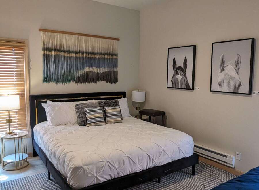 Step into this inviting bedroom, featuring a stylish black bed frame and a cozy, patterned rug.