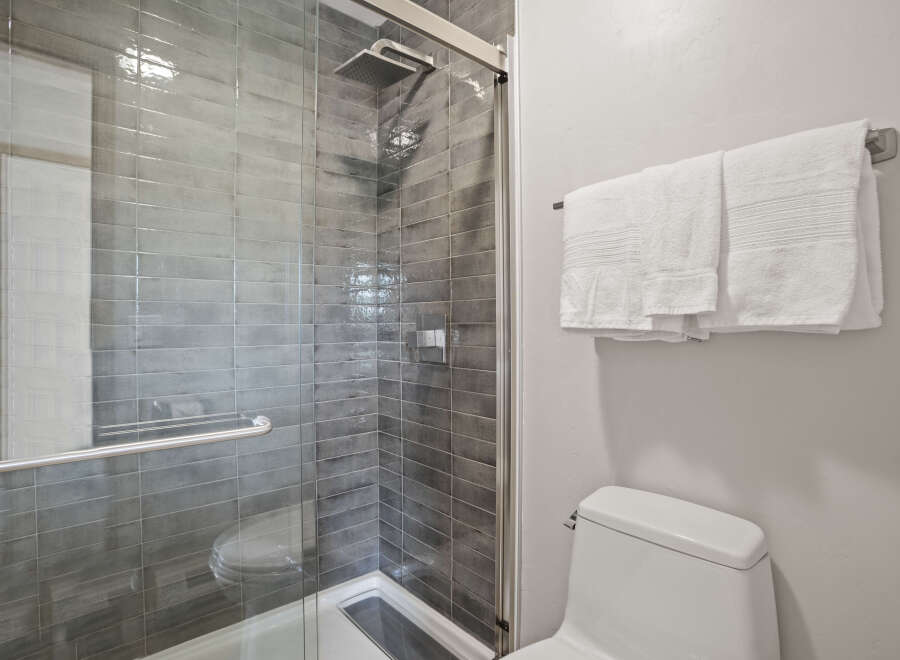 Step into a modern bathroom oasis! This stunning space features a sleek glass-enclosed shower with stylish gray tile, offering a spa-like experience.
