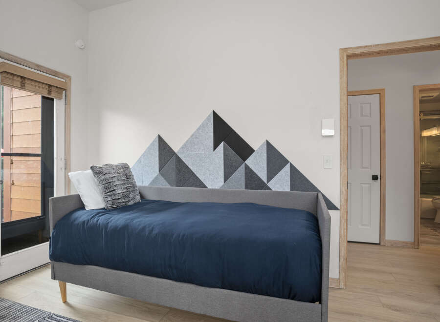 This cozy bedroom features a stylish mountain-themed accent wall, creating a unique and inviting atmosphere.