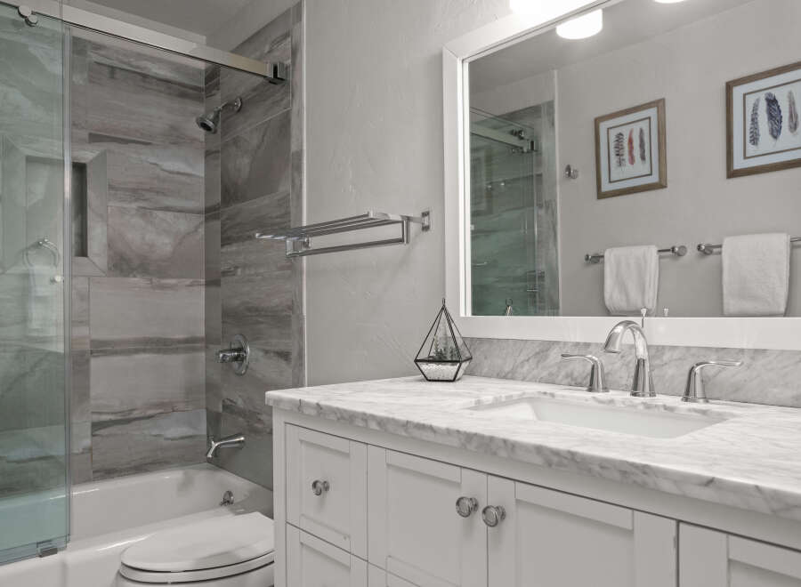 This stunning bathroom features a modern design with a marble countertop and white cabinetry, creating a clean and elegant look.